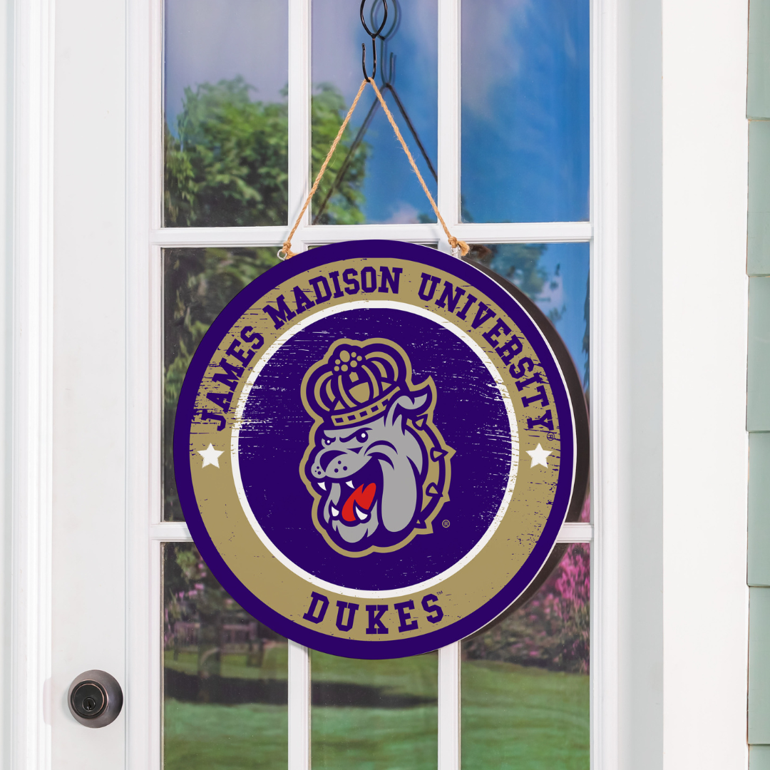 James Madison University Dukes logo on a purple and gold sign hanging on a door.
