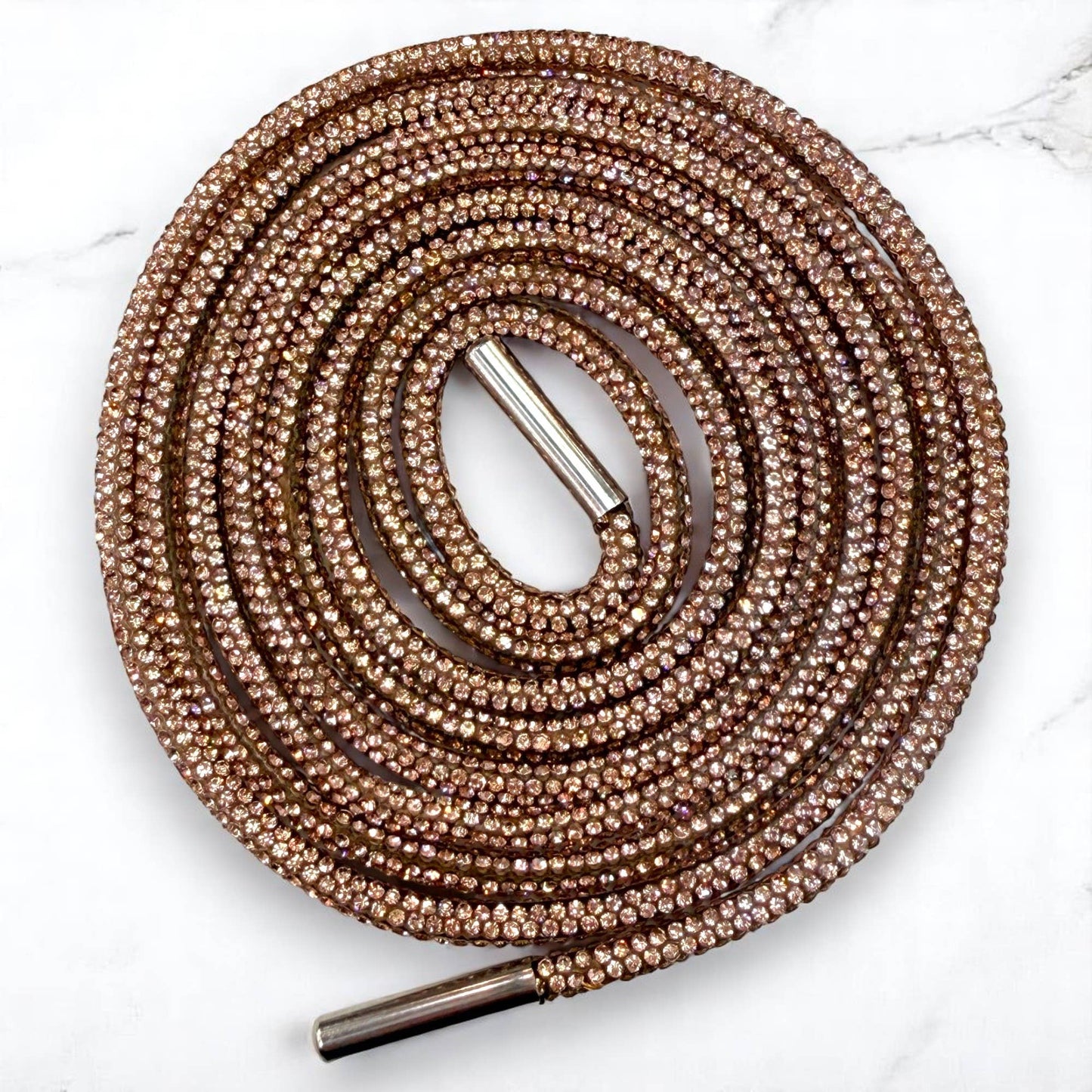 Round, rose gold shoelace with metal eyelets on a white background