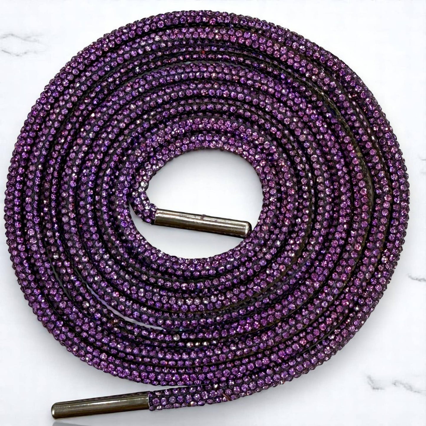 Purple shoelace with metal eyelets on a white marble background