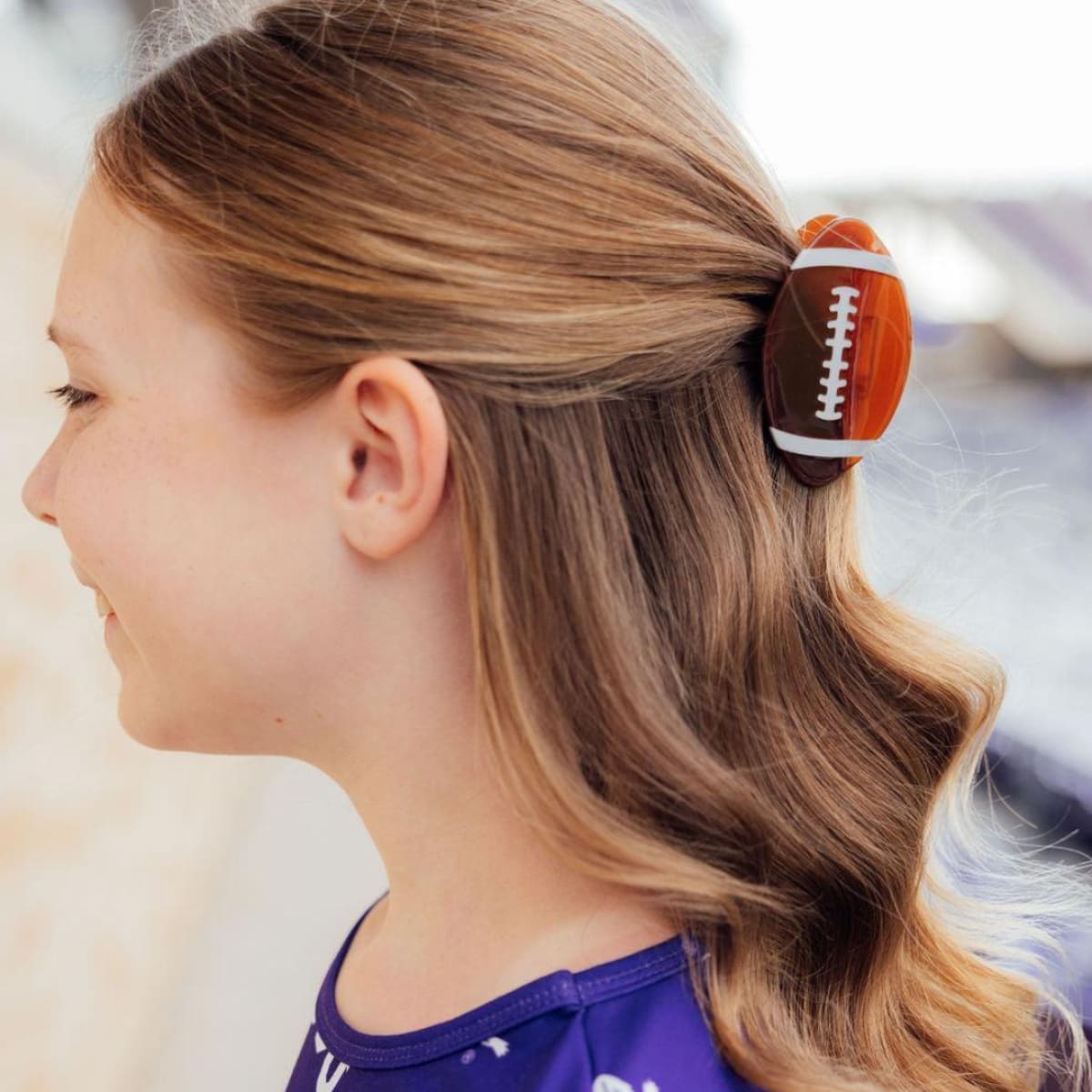 Girl with blonde hair tied back with a football-shaped hair tie.