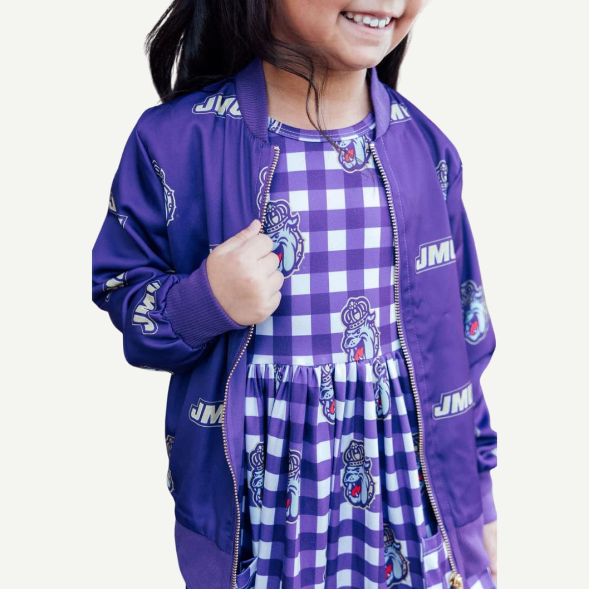 Child wearing a purple jacket and checkered dress with visible branding