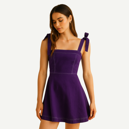 Woman wearing a purple dress with bow straps on a white background