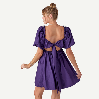 Woman wearing a purple dress with cut-out back on a white background