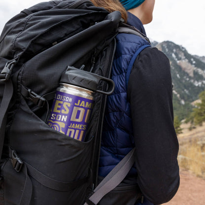 Person with a backpack holding a Jameson whiskey tumbler in a mountainous landscape