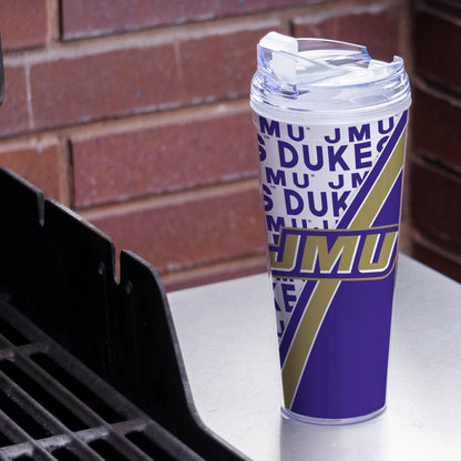 Tumbler with 'JMU DUKES' design on a surface with a brick wall background