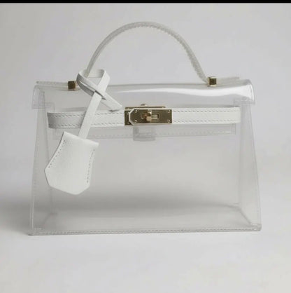 Clear handbag with white interior and gold clasp on a light gray background