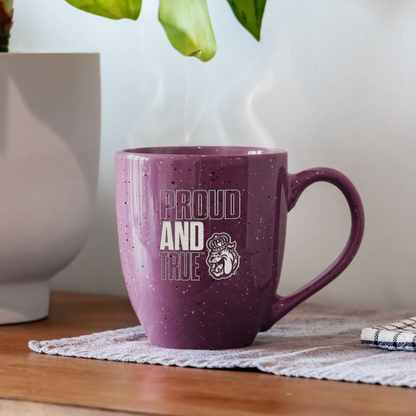 Purple mug with 'Proud and True' text on a wooden surface with a plant in the background