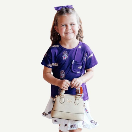Young girl in a purple sports jersey holding a beige handbag on a white background