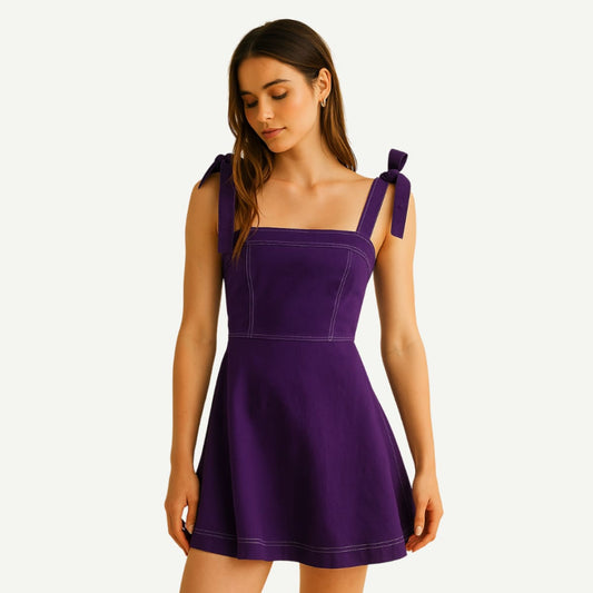 Woman wearing a purple dress with bow straps on a white background