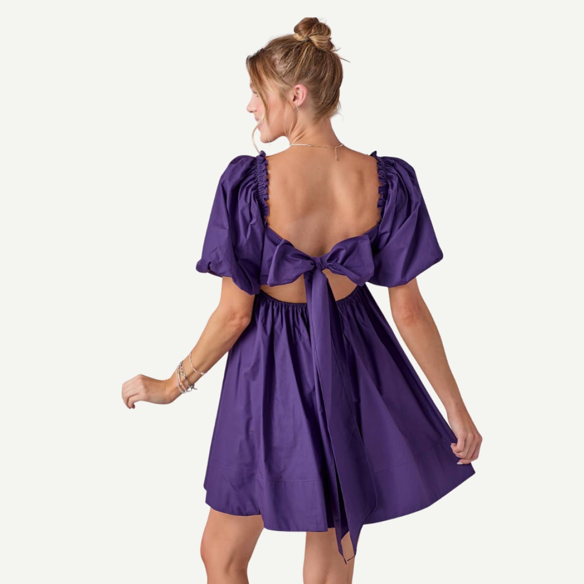 Woman wearing a purple dress with cut-out back on a white background