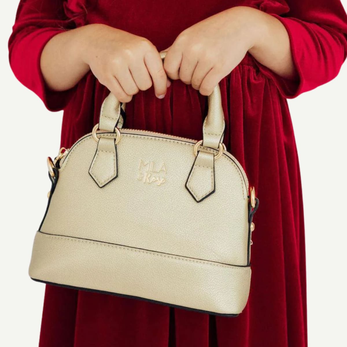 Beige handbag held by a person wearing a red dress on a white background
