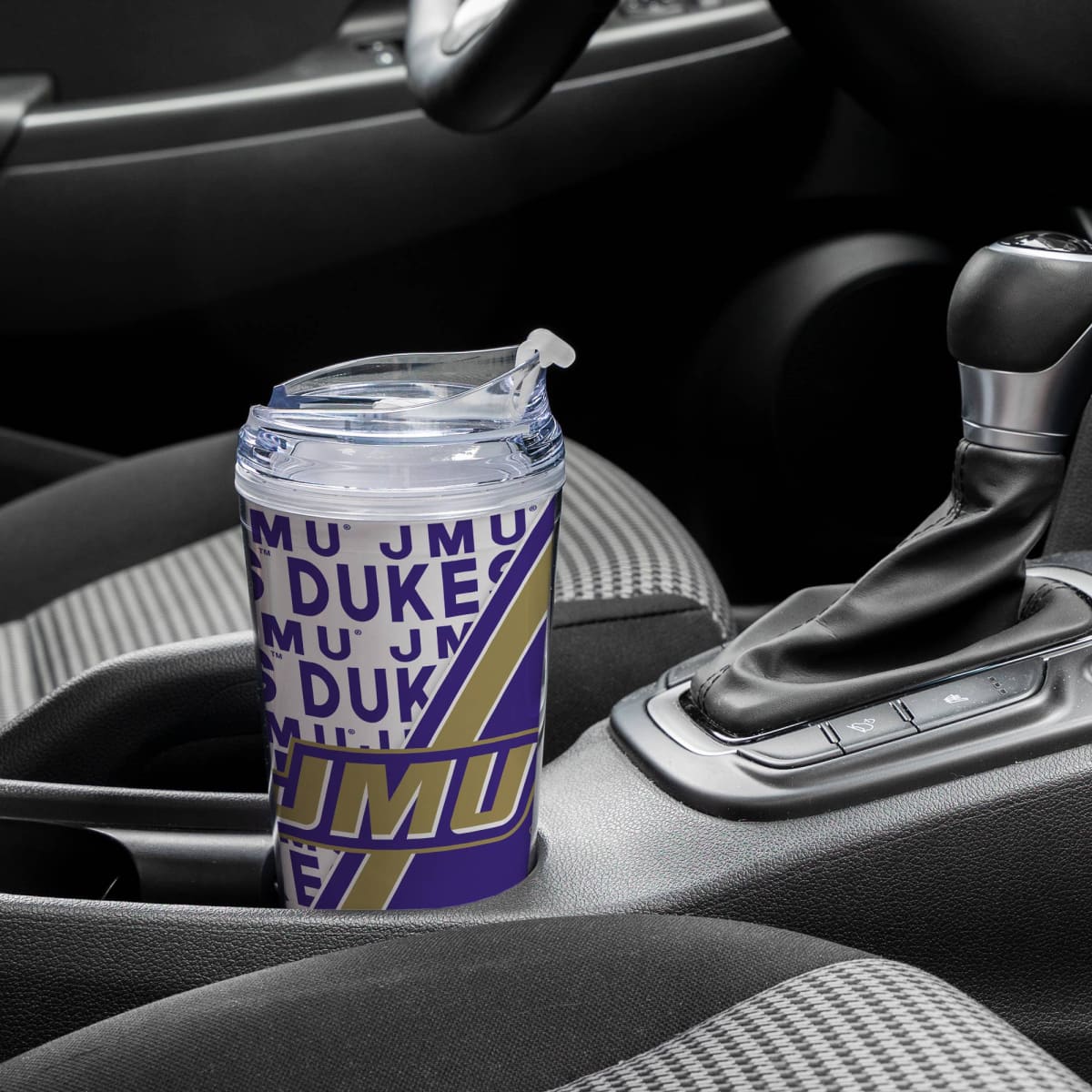 Tumbler with 'MU DUKES' text on a car dashboard