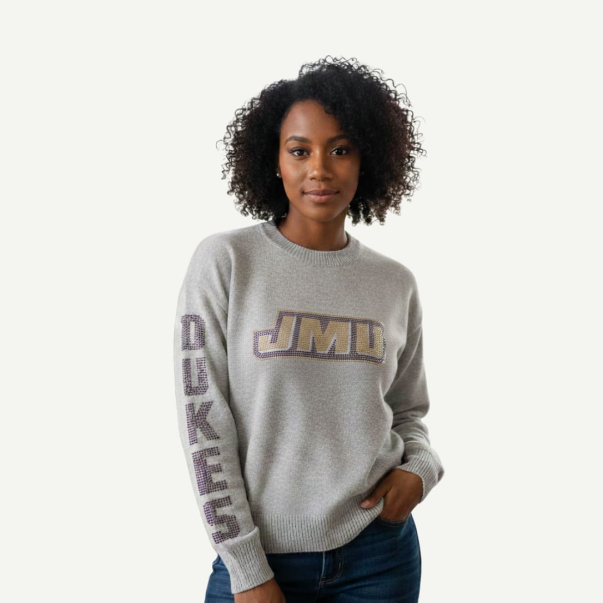 Woman wearing a gray sweater with 'JMU' and 'Dukes' text on a white background