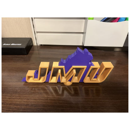 Top view of the JMU Desk Decor displaying the hollow gold letters and purple background shaped like Virginia.