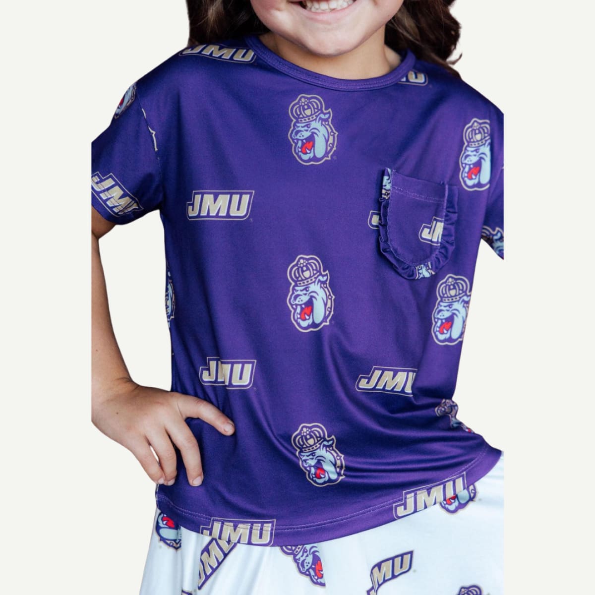 Child wearing a purple shirt and white pants with 'JMU' branding on a plain background