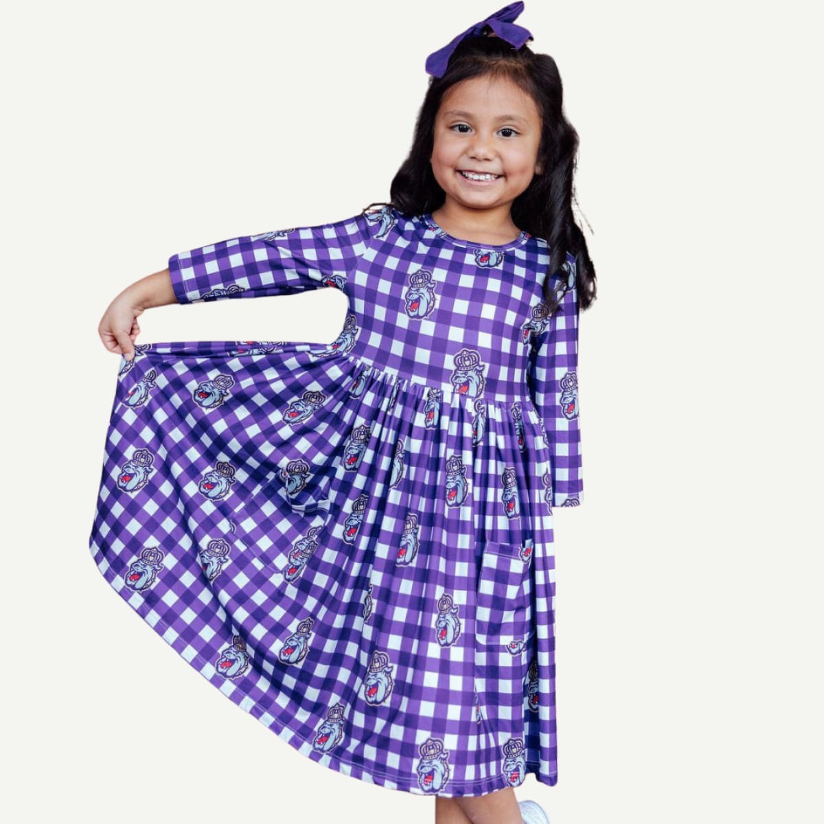 Child wearing a purple checkered dress with cartoon characters on a white background