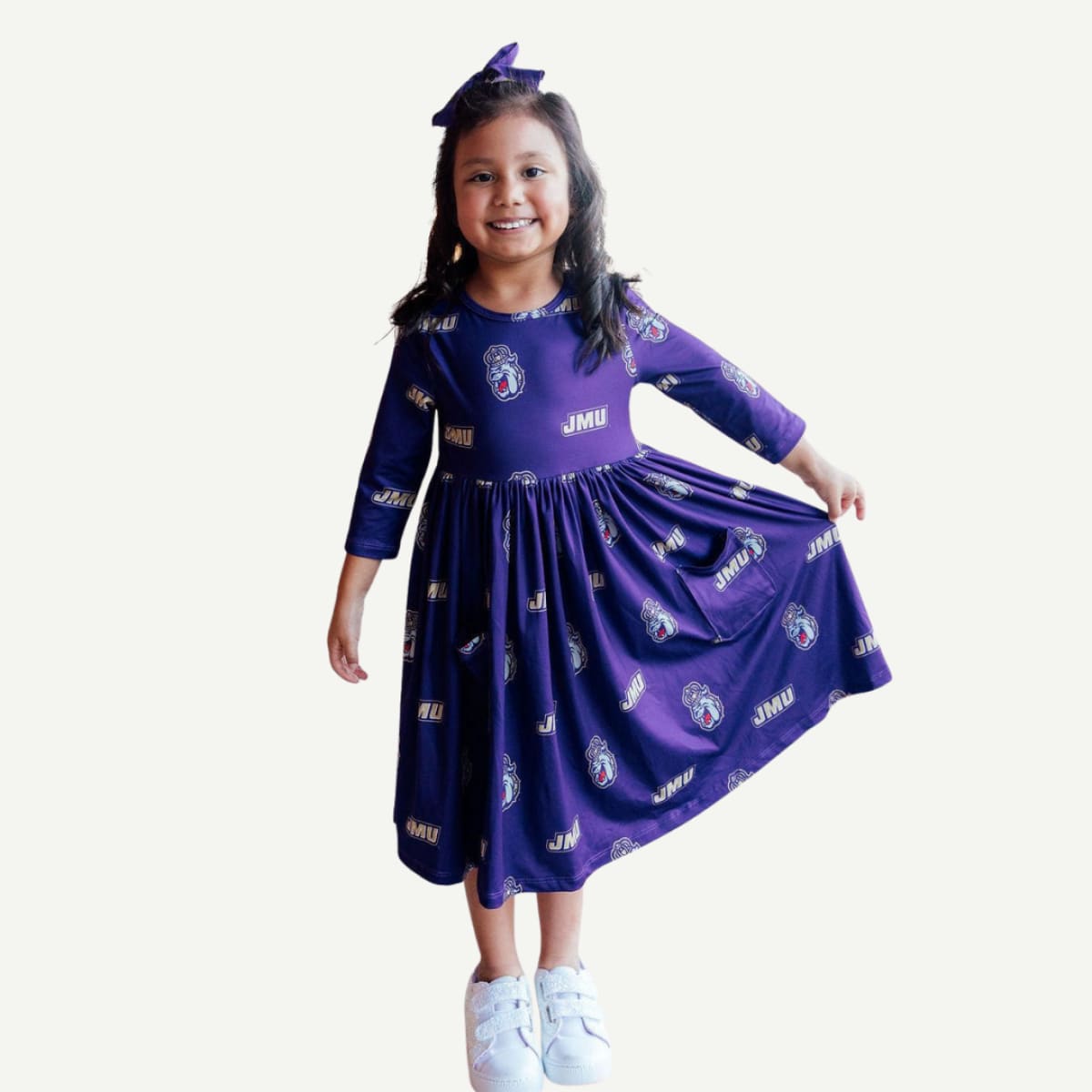 Young girl wearing a purple dress with logos on a white background