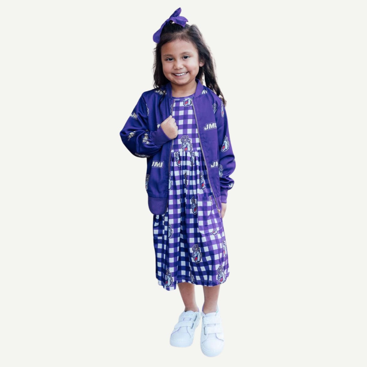 Young girl wearing a purple jacket and checkered dress on a white background
