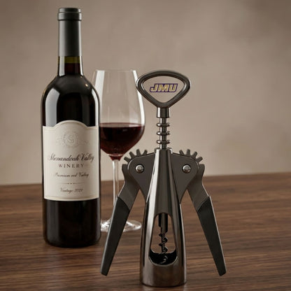 Wine bottle, glass, and corkscrew on a wooden surface with a neutral background