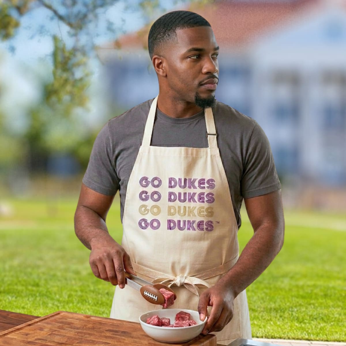 Man wearing a 'Go Dukes' apron outdoors