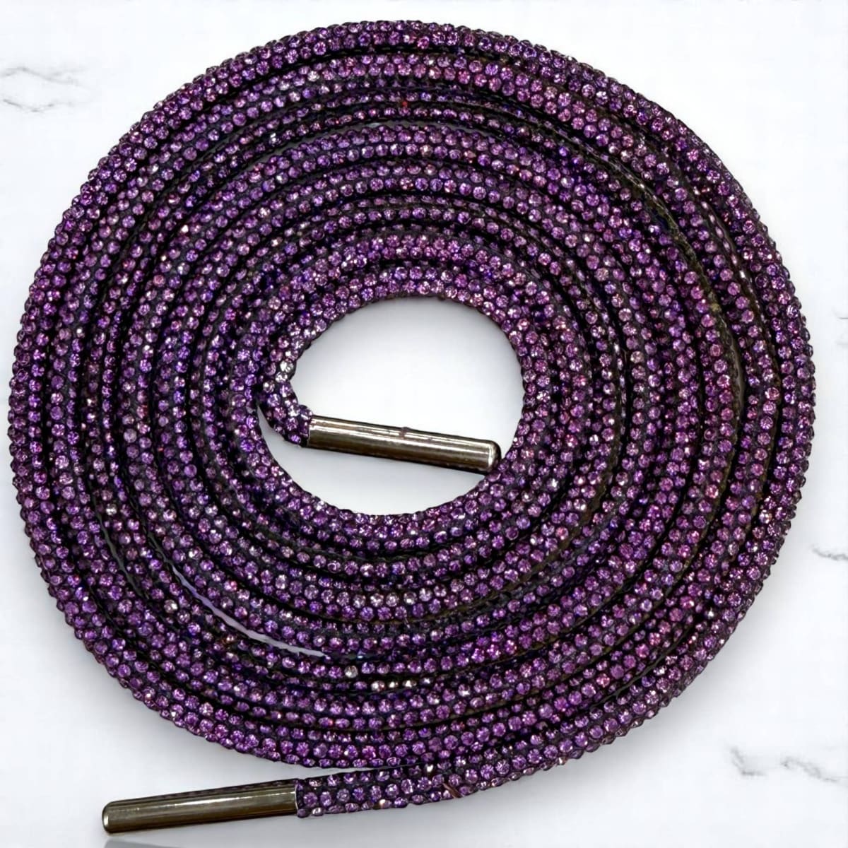Purple shoelace with metal eyelets on a white marble background